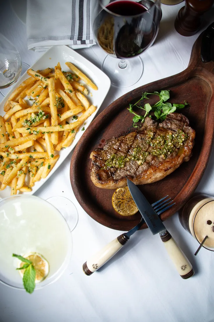 New York steak with chimichurri, fries and a glass of red wine